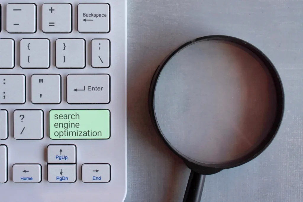 Magnifying glass beside a keyboard with a search engine optimization key